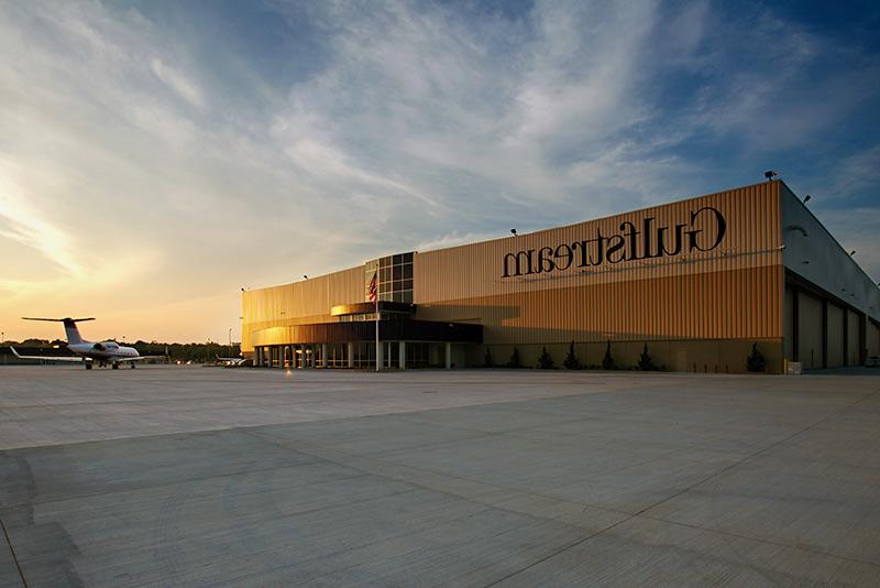 Exterior of Gulfstream Service Center at dusk. Airplane sitting outside of large rectangular building.